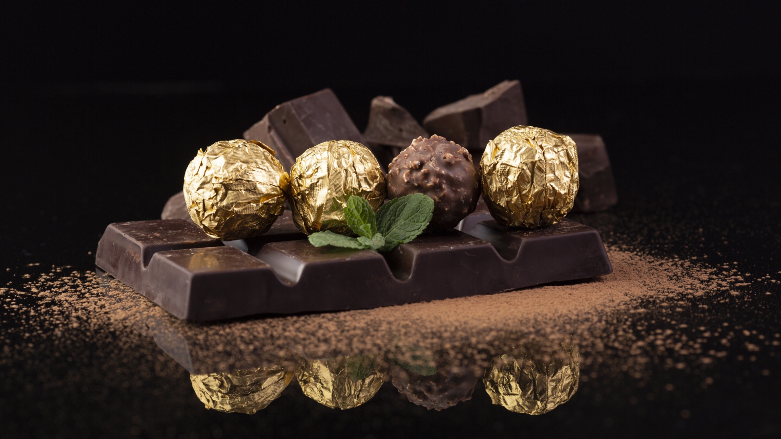 Плитки черного шоколада с конфетами на столе 