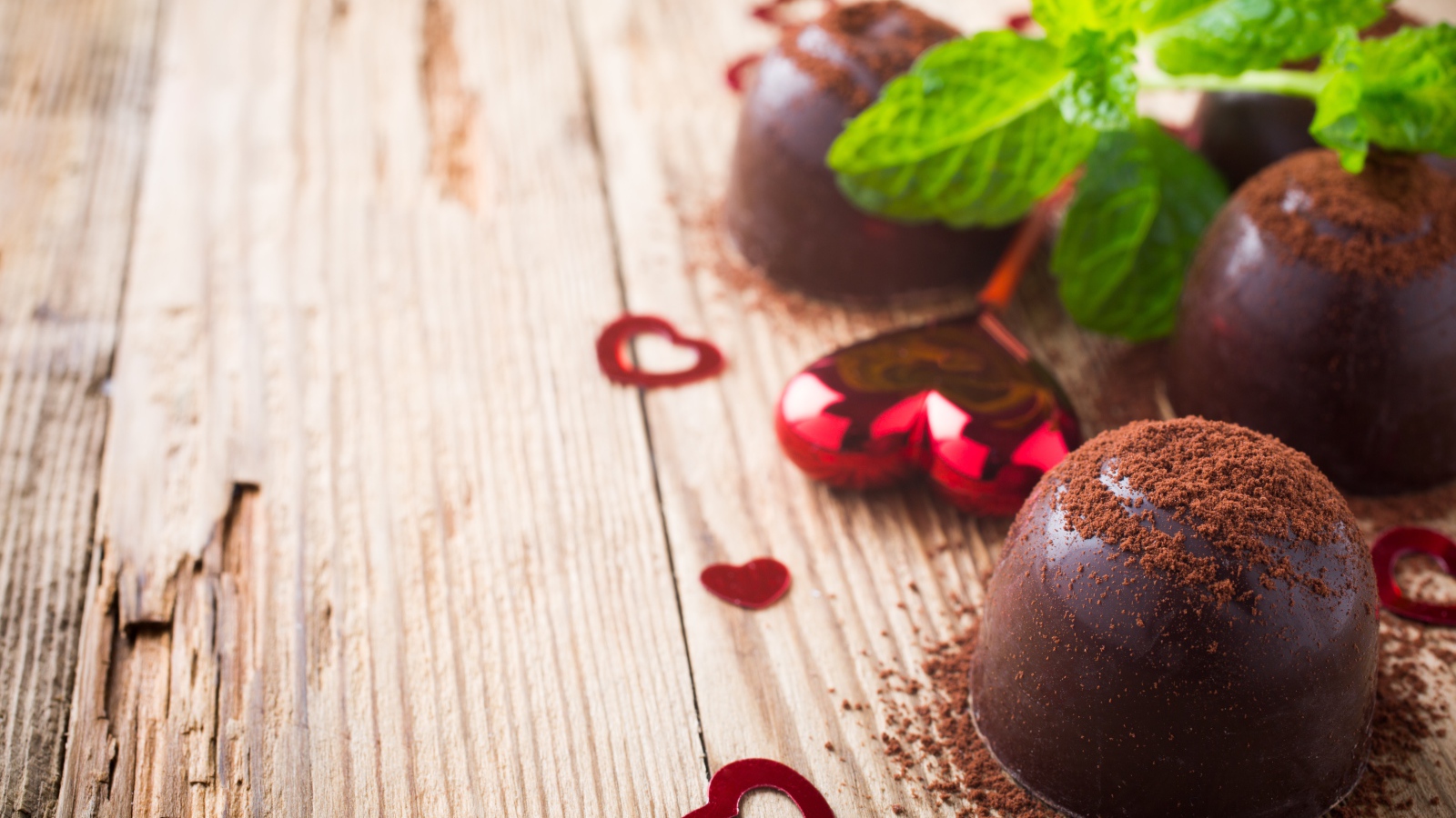 Шоколадные конфеты с какао на столе с мятой и сердечками