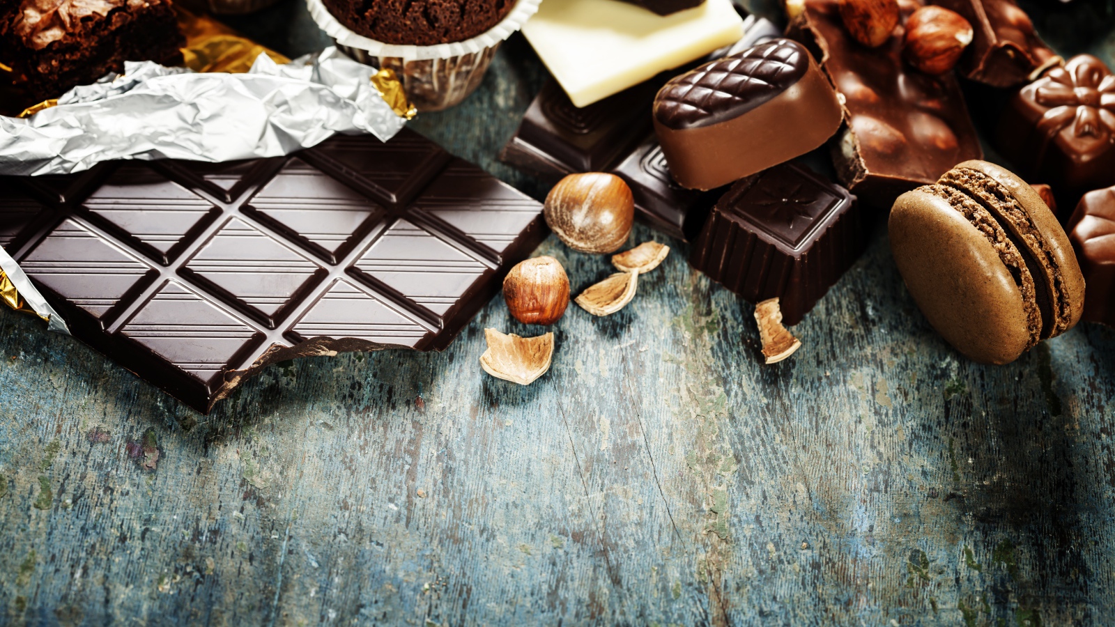 Шоколад на столе с орехами, кексами и конфетами 