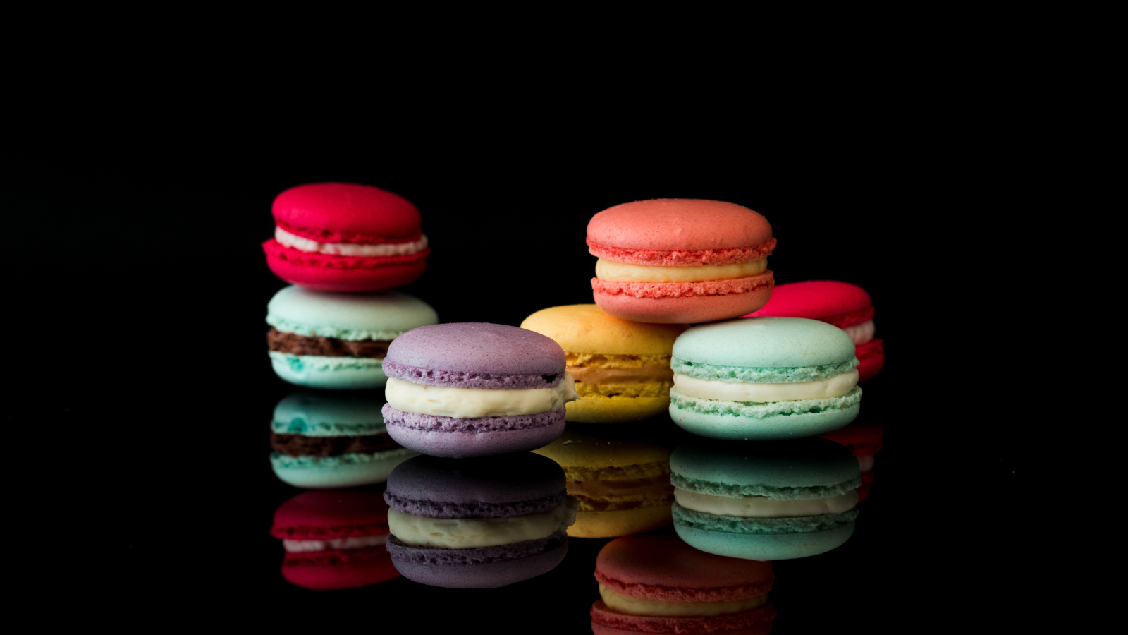 Разноцветный десерт макарун на черном фоне