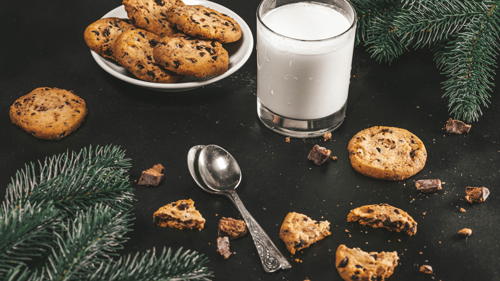 Печенье на столе с молоком и еловыми ветками