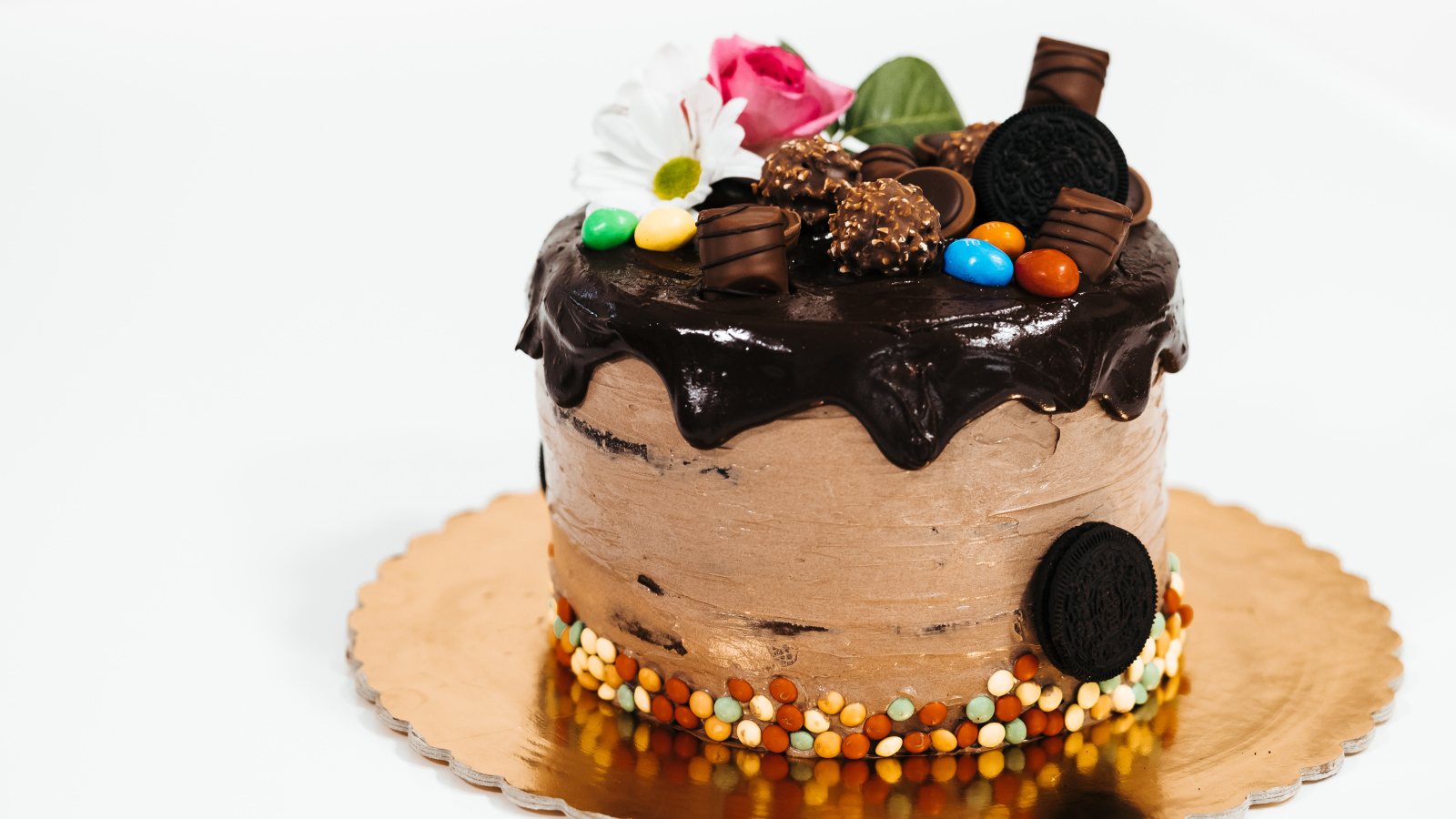 Торт с кремом и шоколадом украшен сладостями