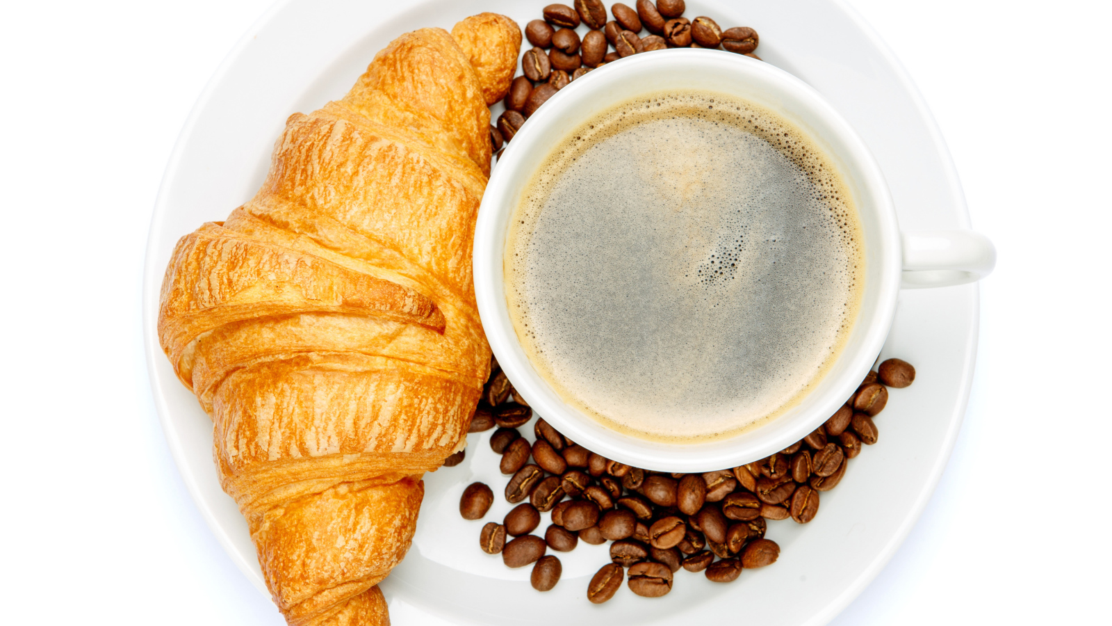 Чашка кофе на белой тарелке с круассаном и зернами, вид сверху 