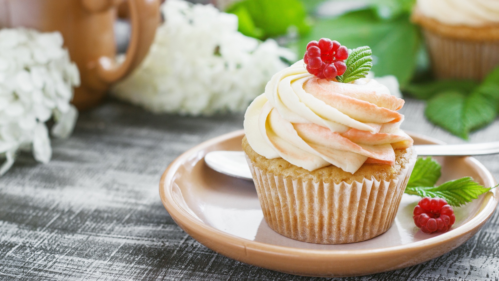 Кекс с кремом и малиной на столе