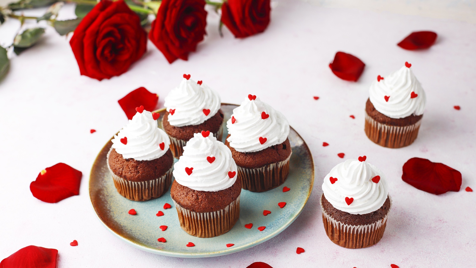 Кексы с кремом на столе с букетом роз 