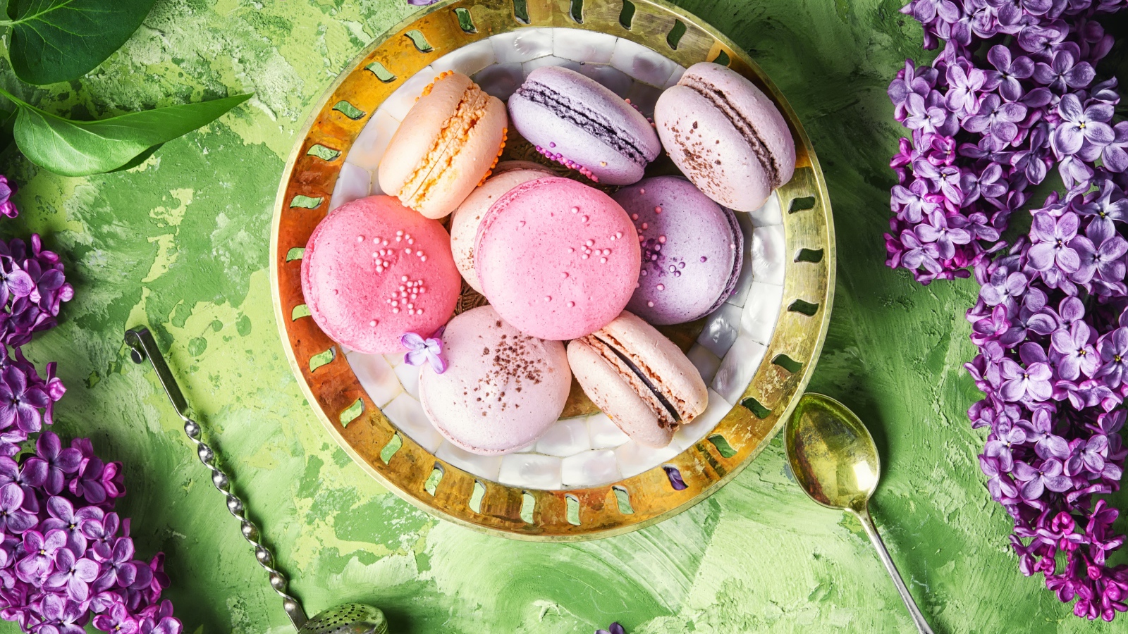 Разный десерт макарон на столе с цветами сирени 