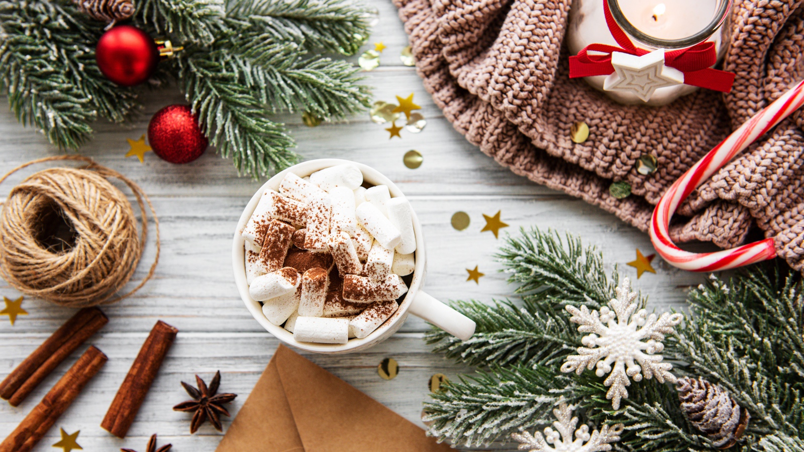 Кружка с маршмеллоу на столе с еловыми ветками и свечой