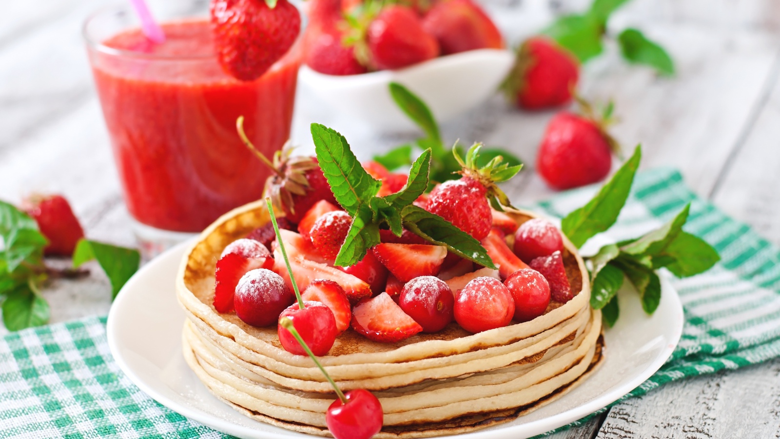 Блины с ягодами клубники  и черешни на белой тарелке