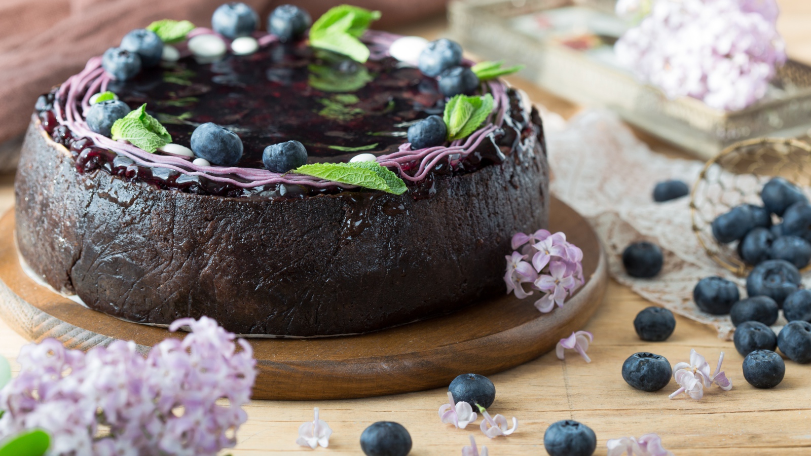 Пирог с джемом и ягодами черники на столе с сиренью 