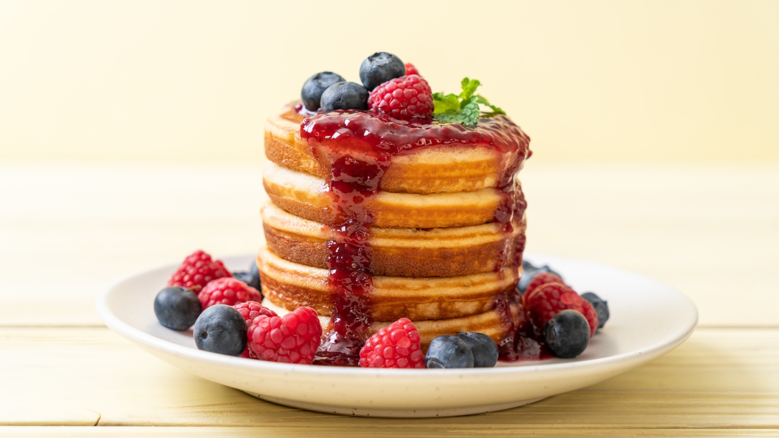 Румяные панкейки с джемом и ягодами черники и малины на тарелке