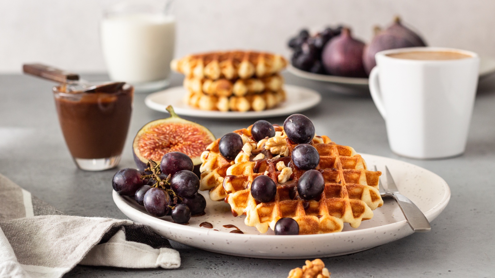 Сладкие вафли на тарелке с инжиром и виноградом