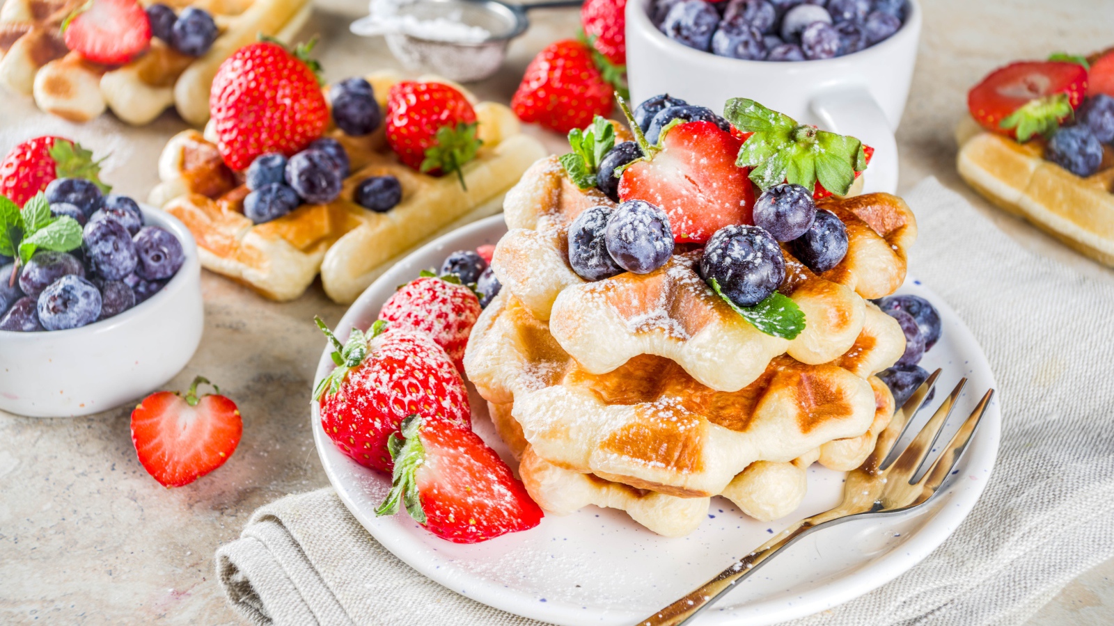 Вкусные сладкие вафли с ягодами клубники, черники и сахарной пудрой