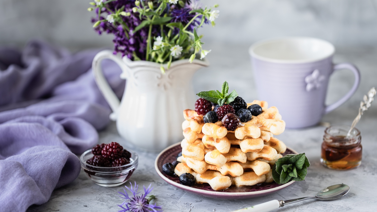 Вафли с ягодами черники и ежевики на столе с букетом