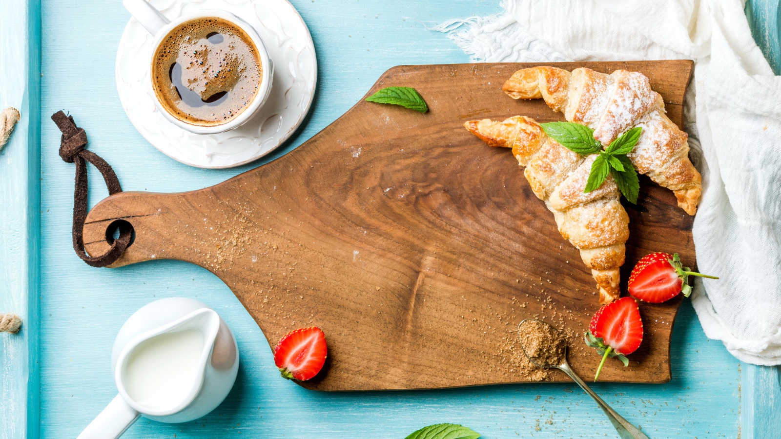 Деревянная доска на столе с круассанами и чашкой кофе