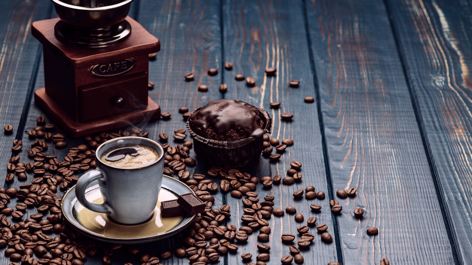 Чашка кофе на столе с шоколадным кексом и кофемолкой