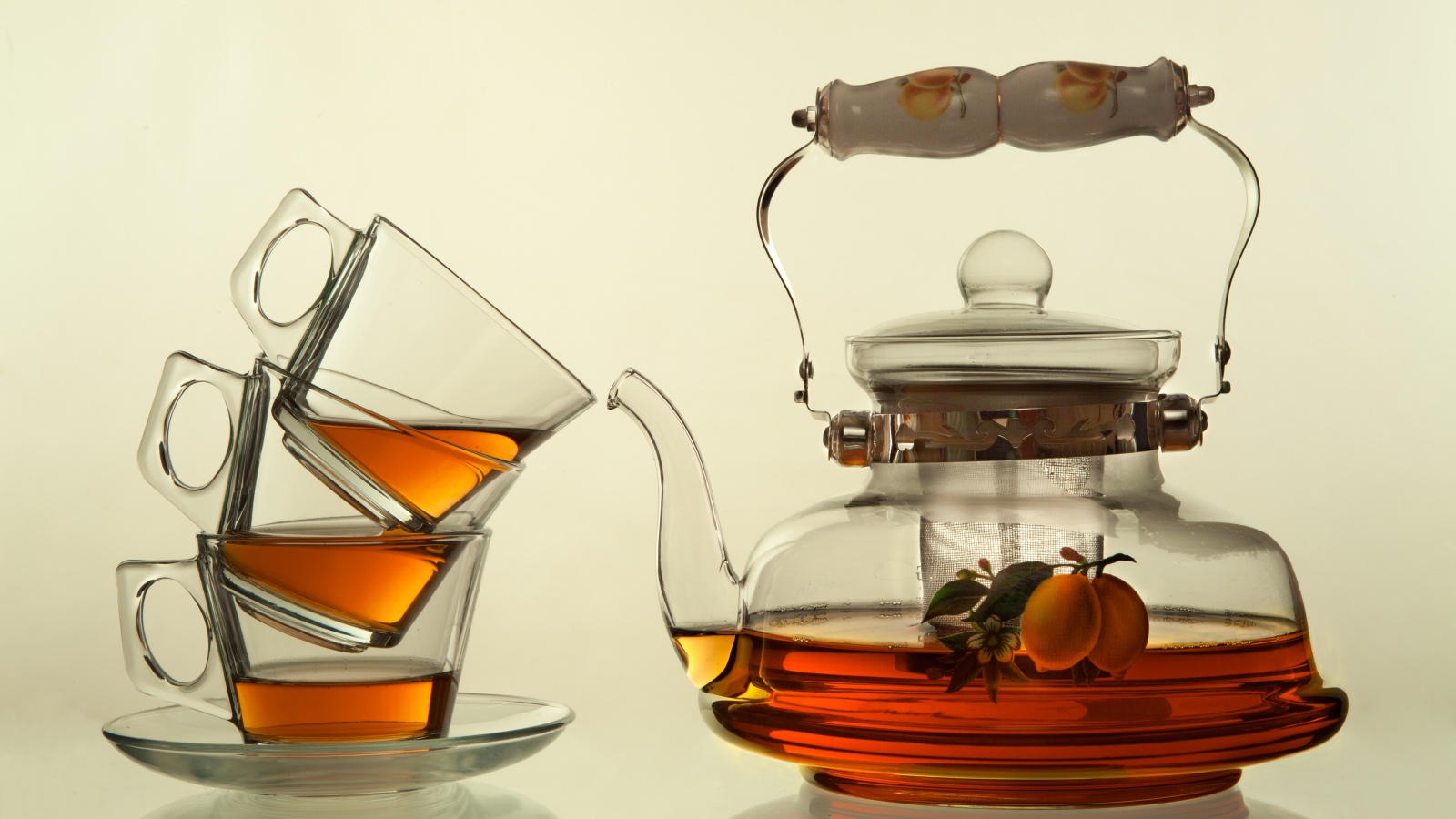 Стеклянный чайник с чашками на белом фоне