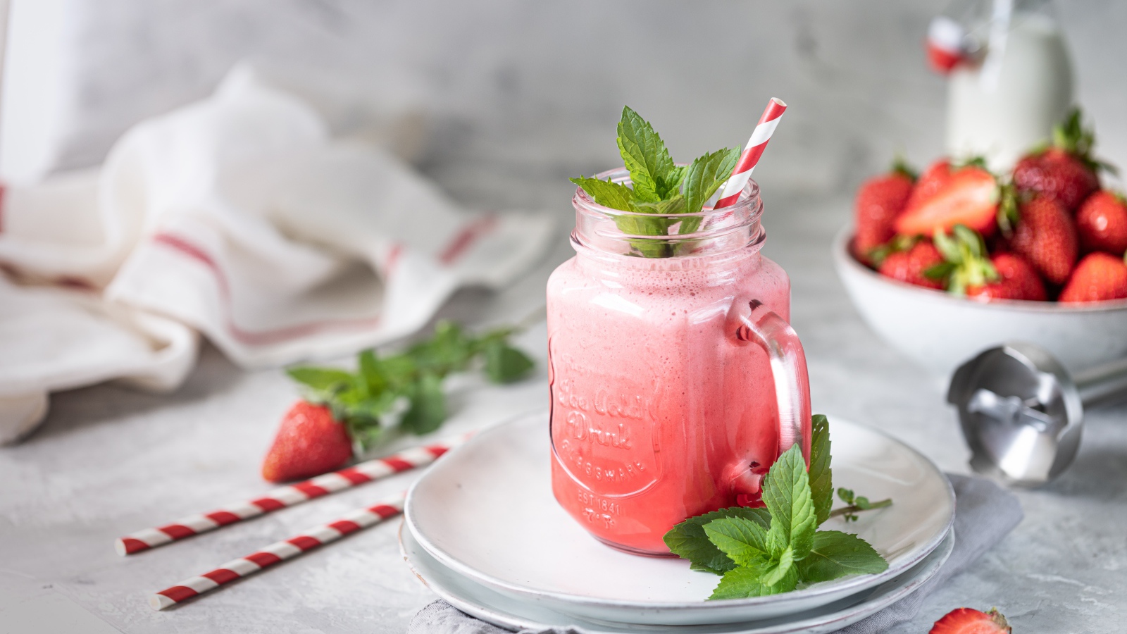 Смузи с клубникой в банке с трубочкой и листьями мяты