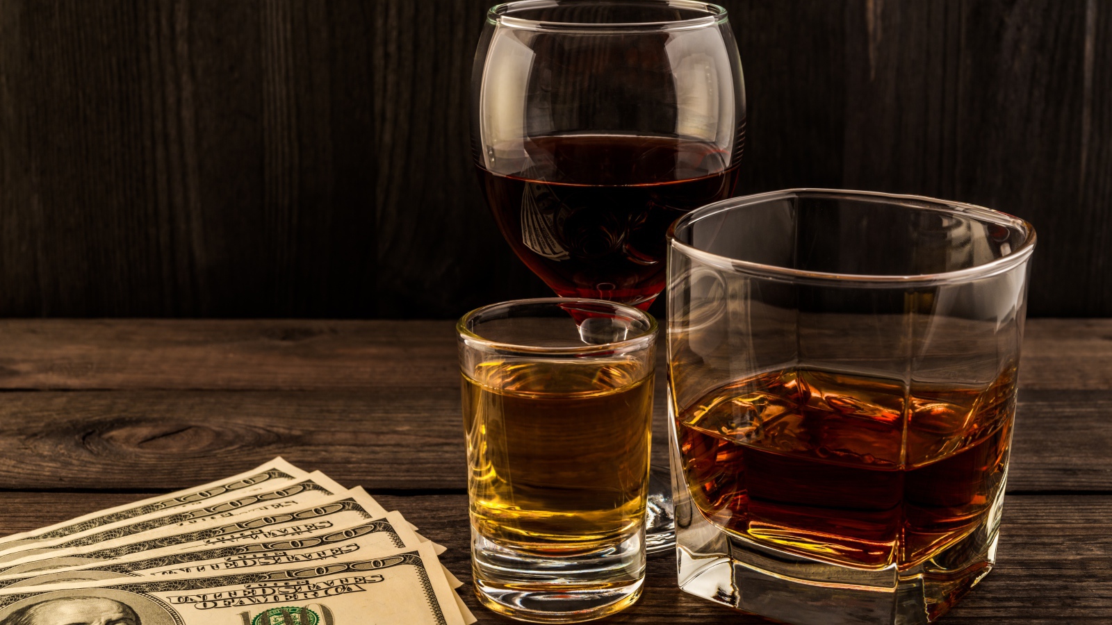 Три сосуда  с виски на столе с долларами