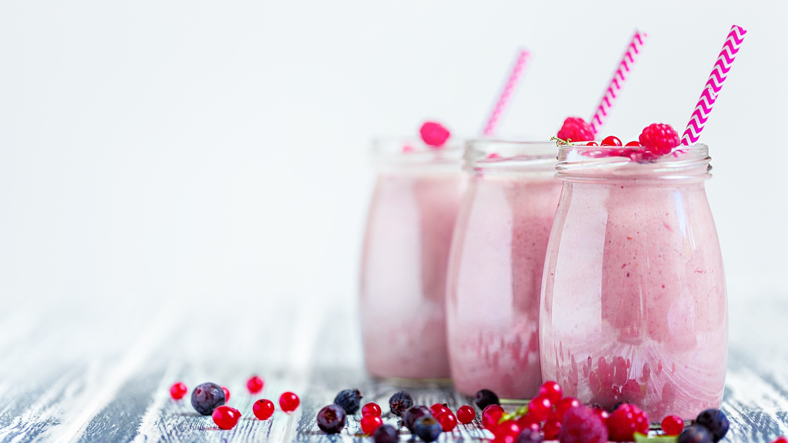 Три банки с ягодным смузи на белом фоне