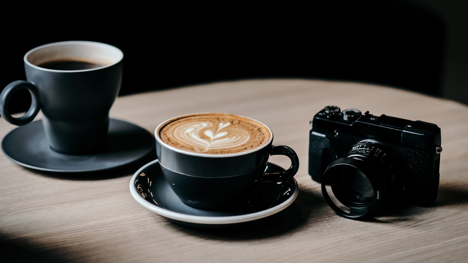 Две чашки кофе на столе с фотоаппаратом 