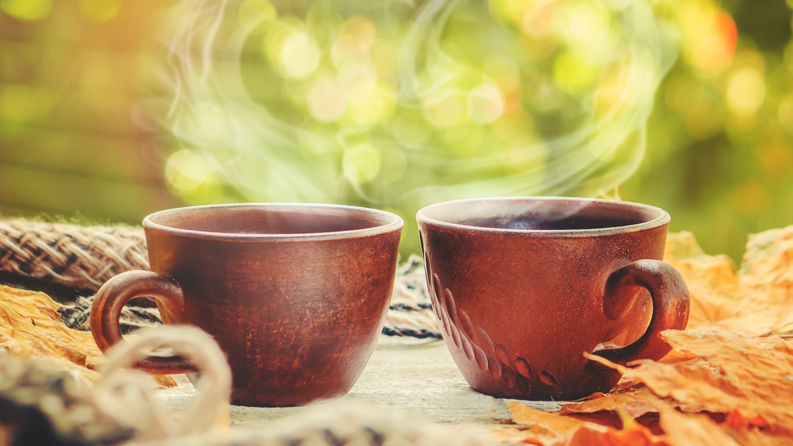 Два чашки горячего кофе с паром на столе осенью 