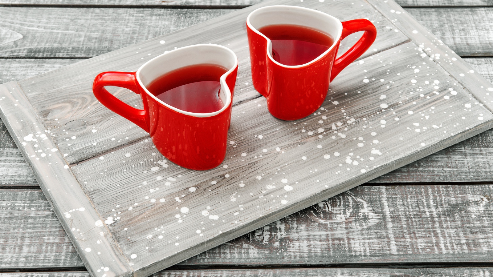 Две красные чашки в форме сердца на столе 