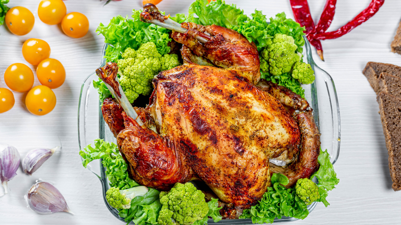 Запеченная курица с брокколи и листьями салата на столе с овощами