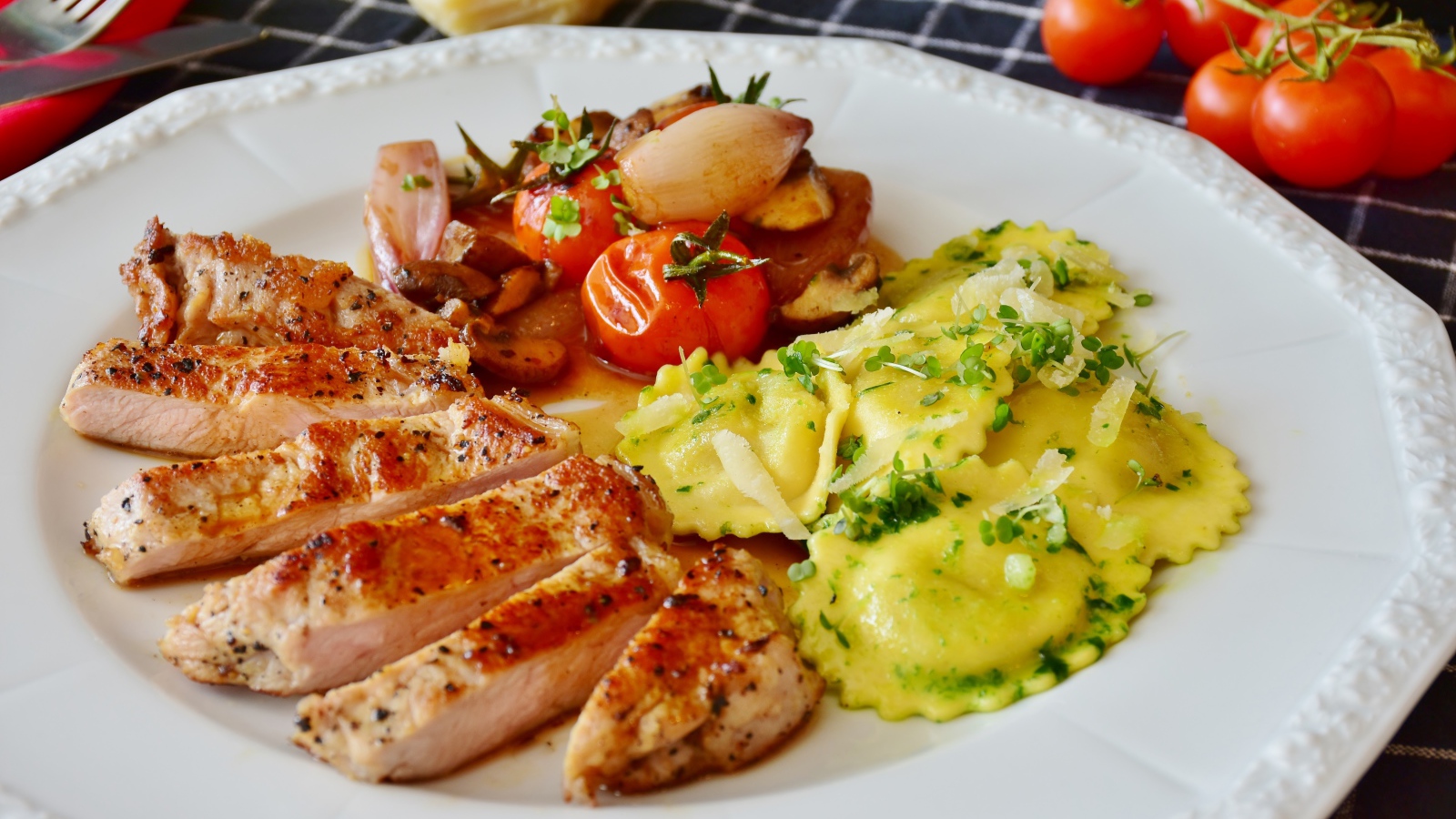 Куриное филе нарезанное кусочками на тарелке с овощами и варениками