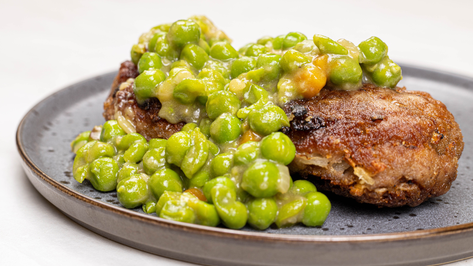 Котлета на тарелке с зеленым горошком