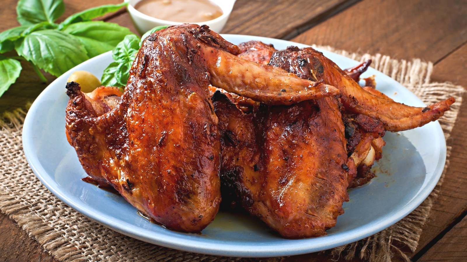 Зажареные куриные крылышки на столе с соусом и базиликом