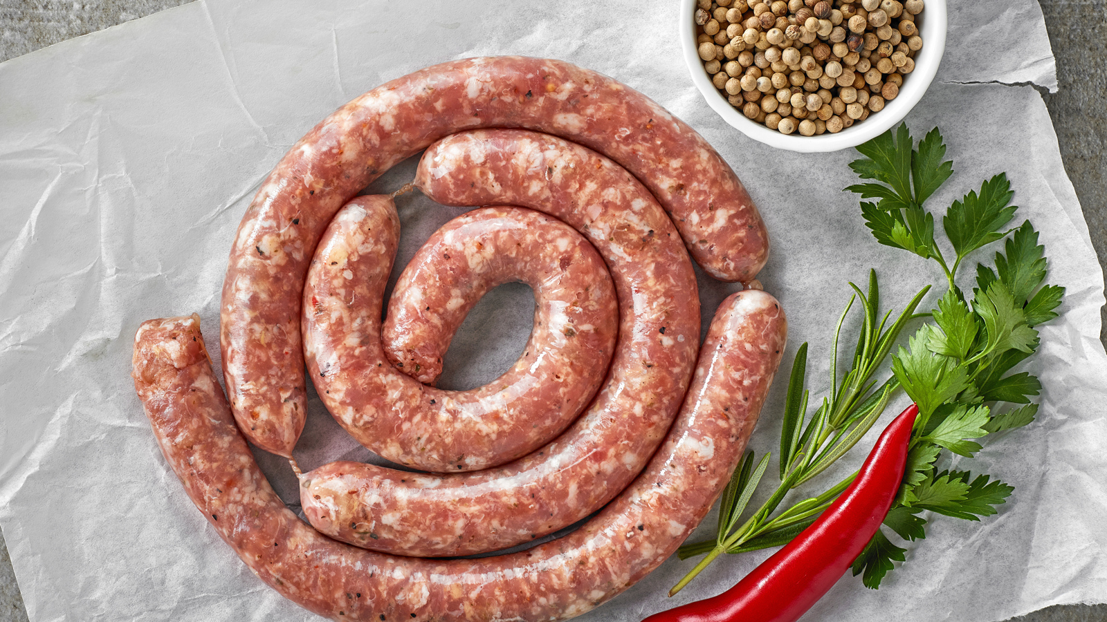 Домашняя колбаса на столе с зеленью и перцем