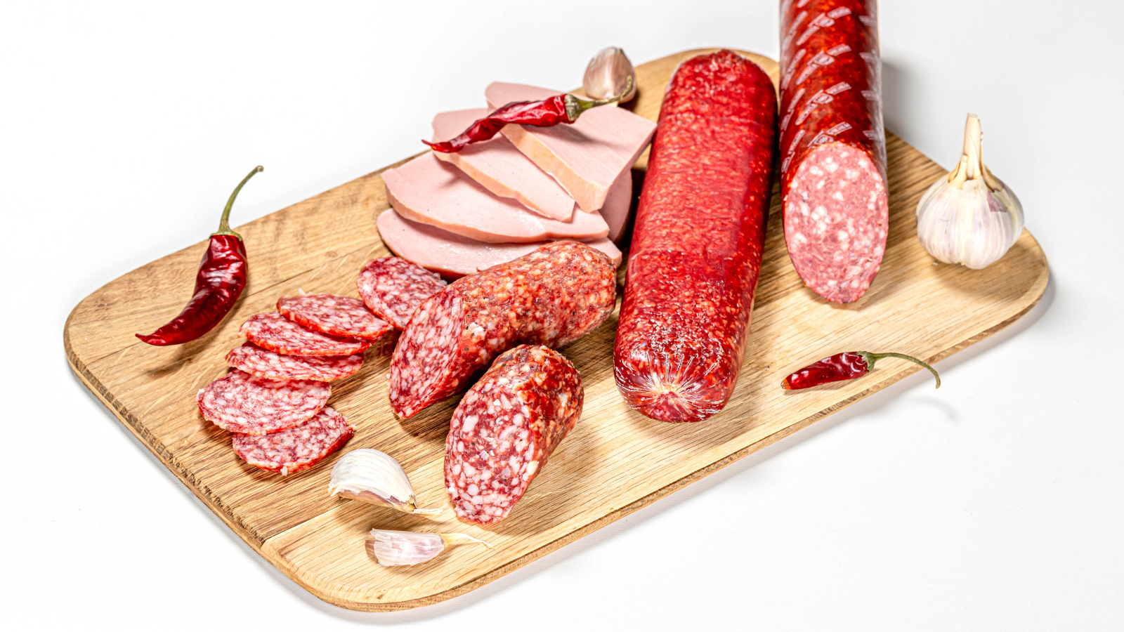 Вкусная колбаса с красным перцем и чесноком на доске на белом фоне
