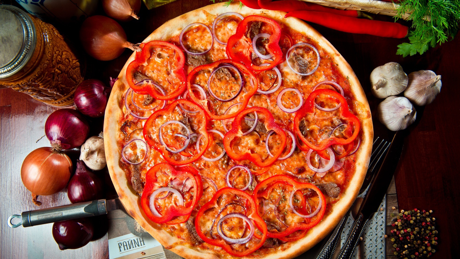 Большая пицца с мясом, луком и болгарским перцем на столе 