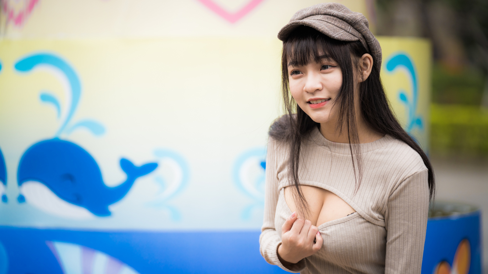 Улыбающаяся девушка азиатка стоит у стены  с рисунком