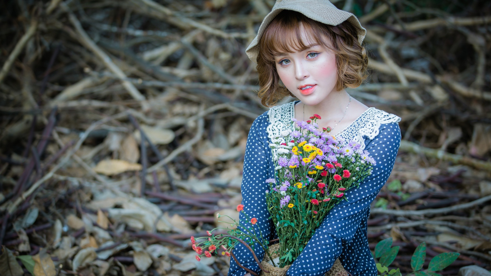 Молодая девушка азиатка с букетом цветов сидит на ветках