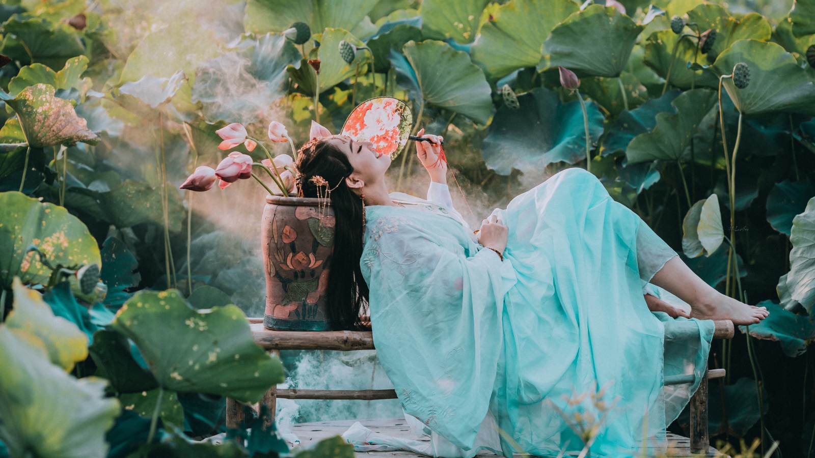 Девушка азиатка в красивом голубом платье на поле лотосов