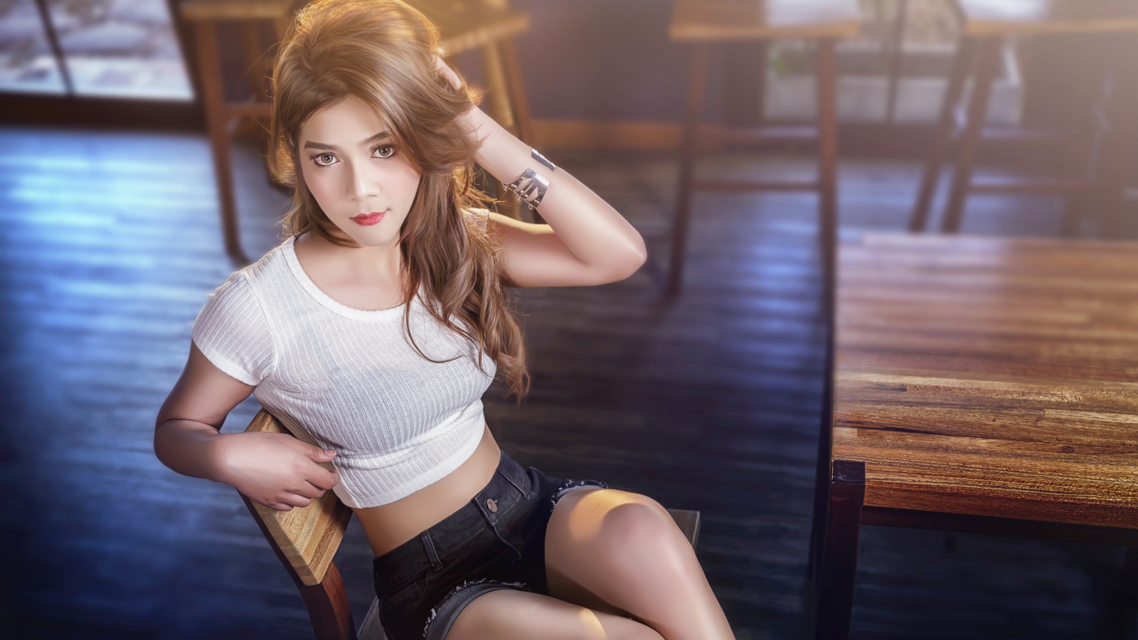 Девушка азиатка сидит на деревянном стуле в кафе