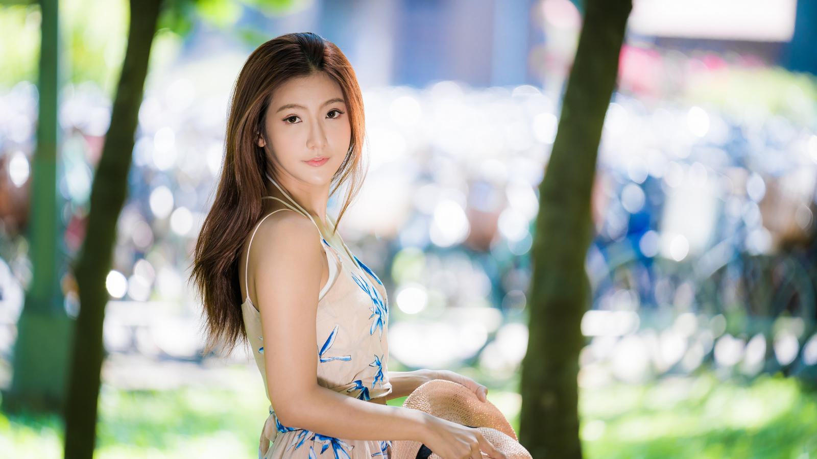 Девушка азиатка со шляпой в руке в парке 