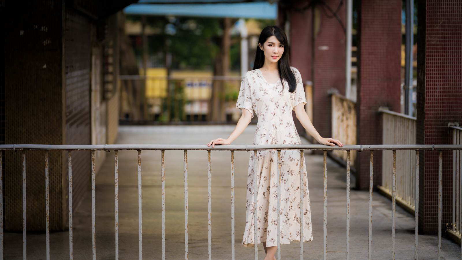 Красивая азиатка в платье стоит у перил