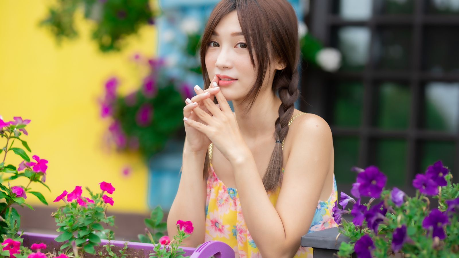 Красивая девушка Азиатка у цветов петунии