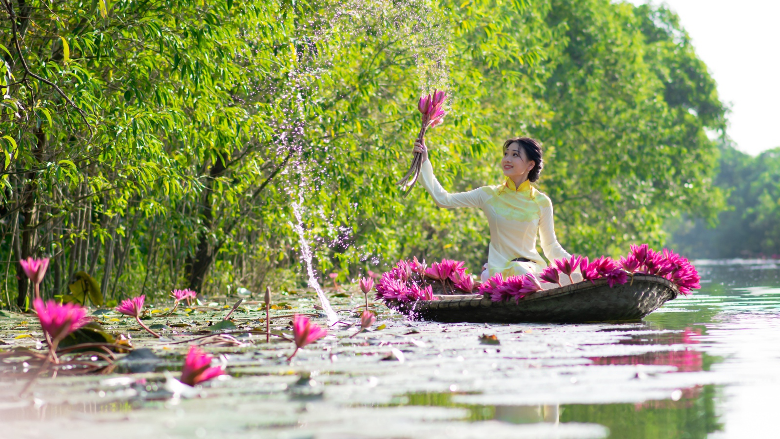 Красивая девушка азиатка на лодке рвет цветы лотоса в реке