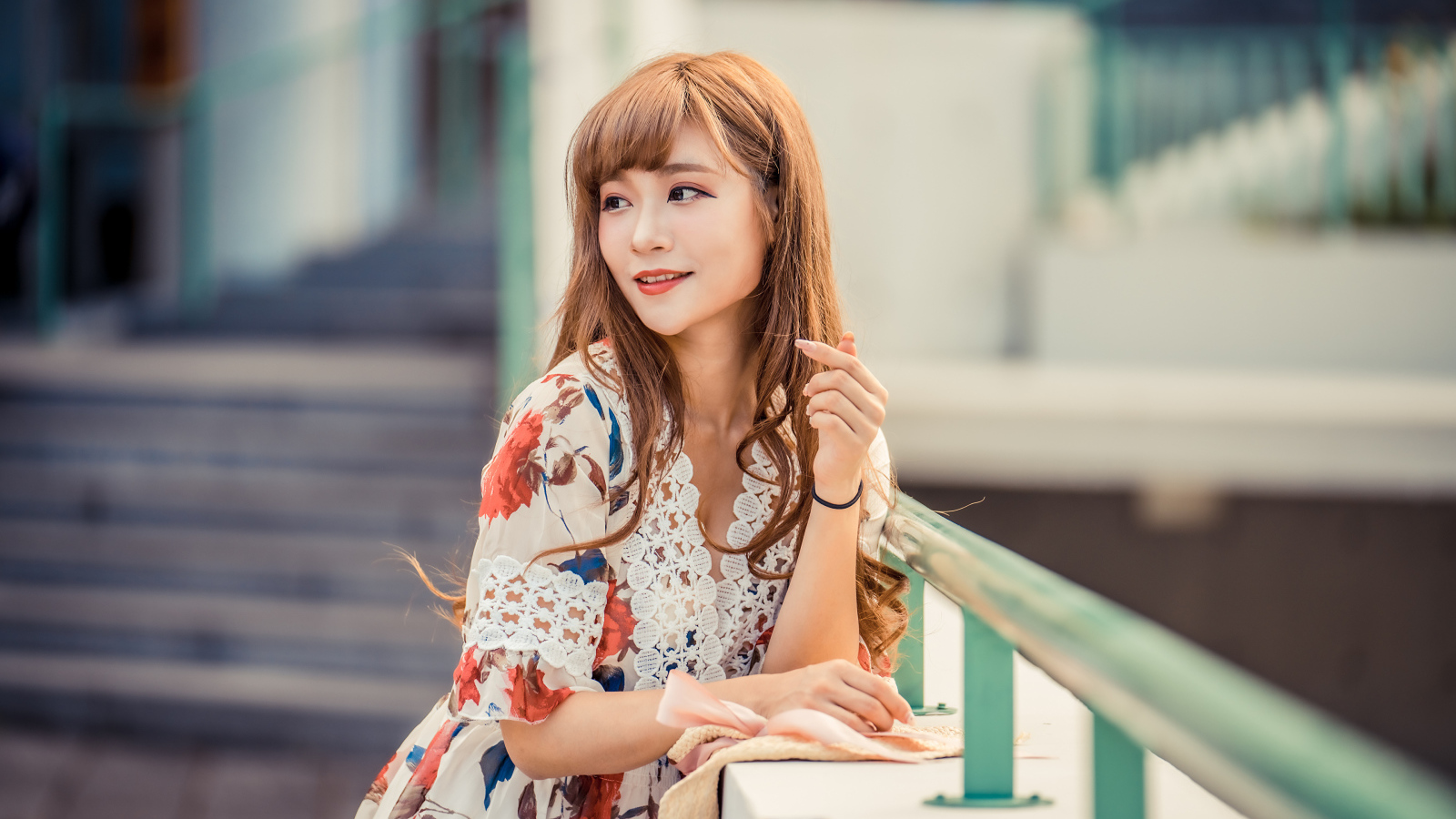 Красивая девушка азиатка стоит у перил 