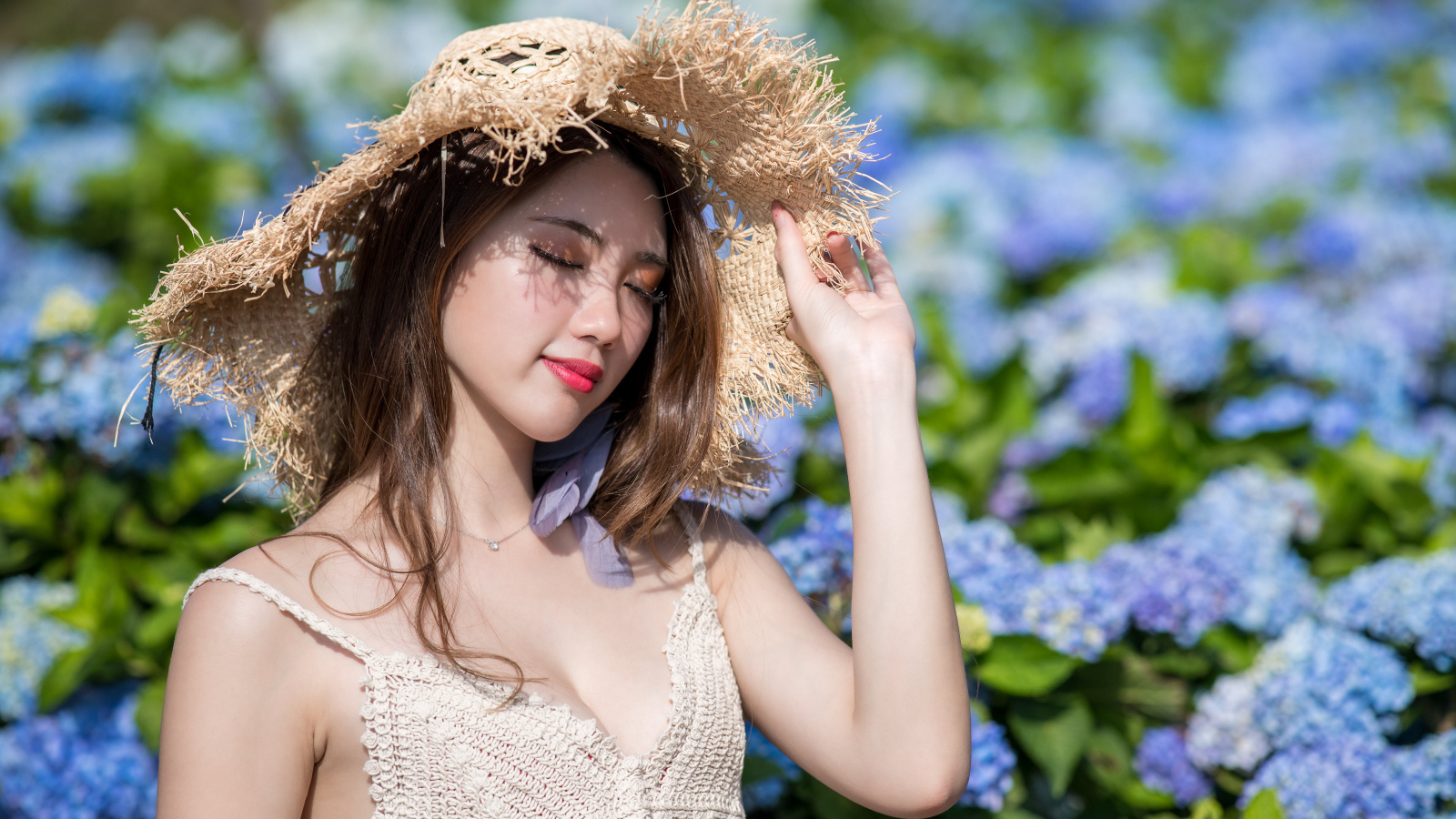 Красивая девушка азиатка с закрытыми глазами на фоне цветов гортензии