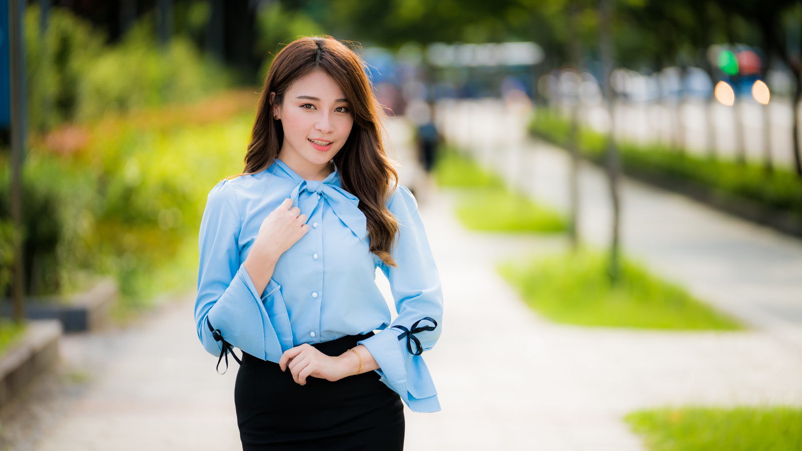 Красивая азиатка в голубой блузке и черной юбке 