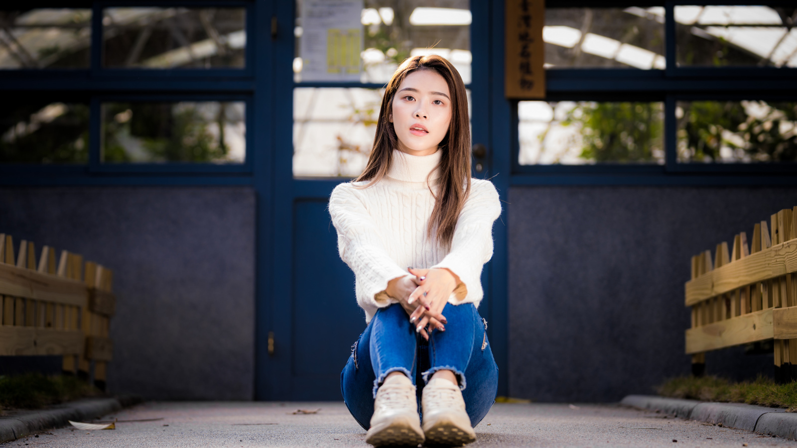 Красивая азиатка в синих джинсах сидит на земле