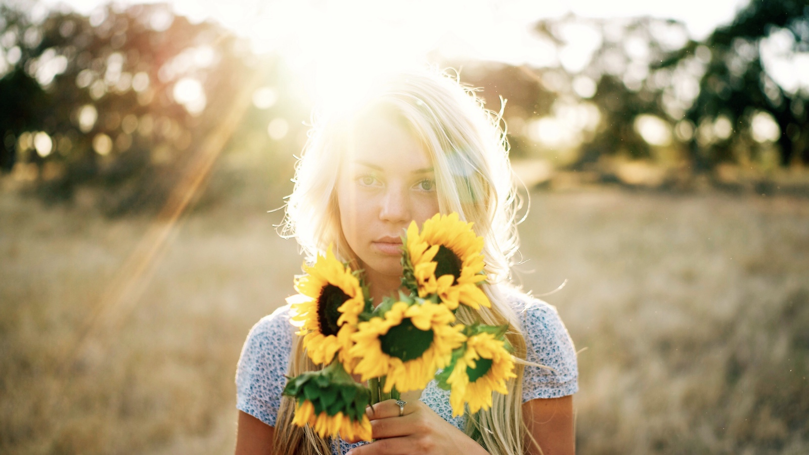 Красивая блондинка с букетом подсолнухов в руках