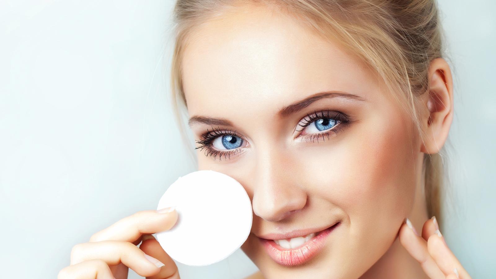 Красивая голубоглазая девушка с ватным диском в руке 