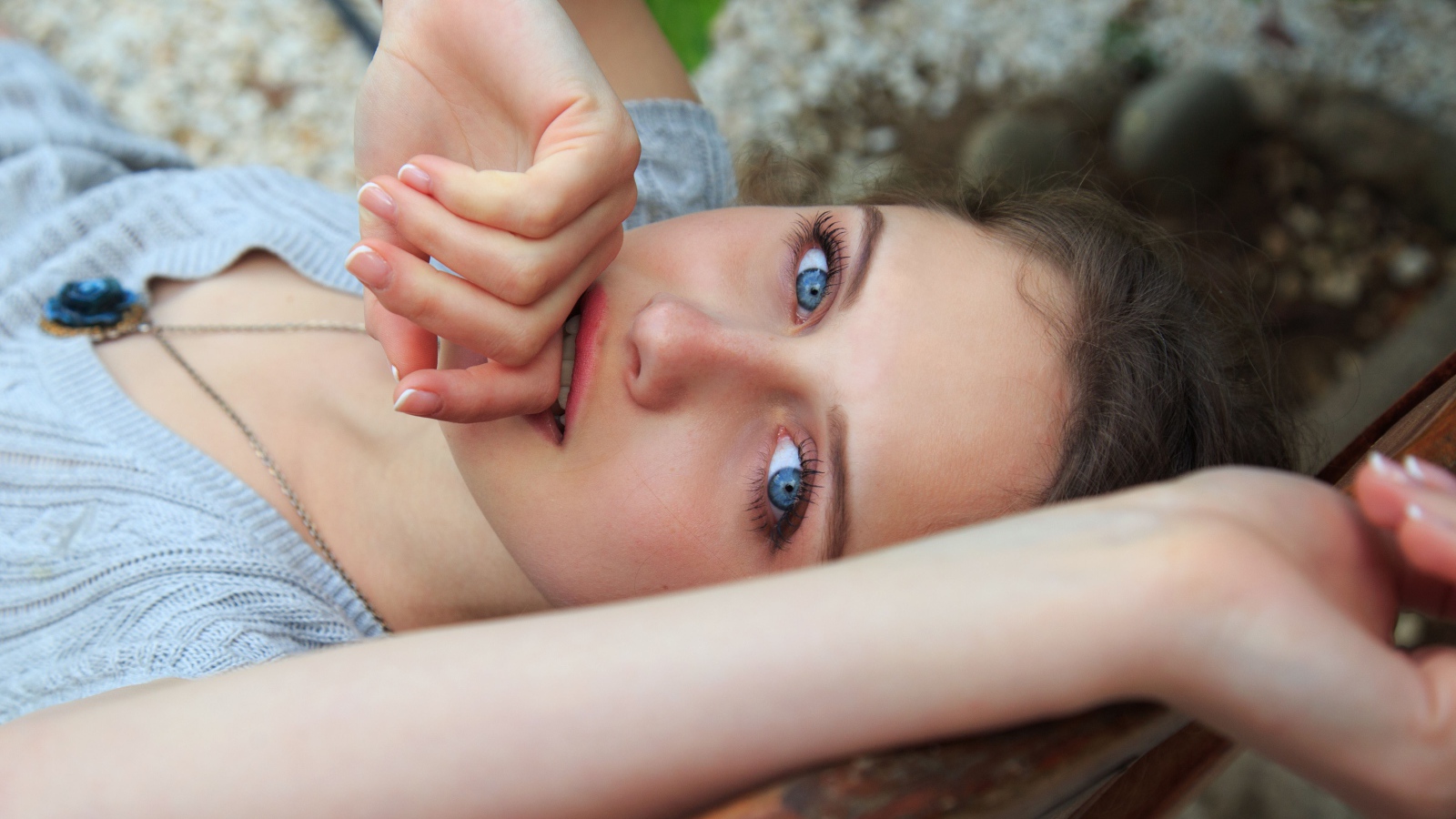 Красивая голубоглазая девушка с рукой у рта