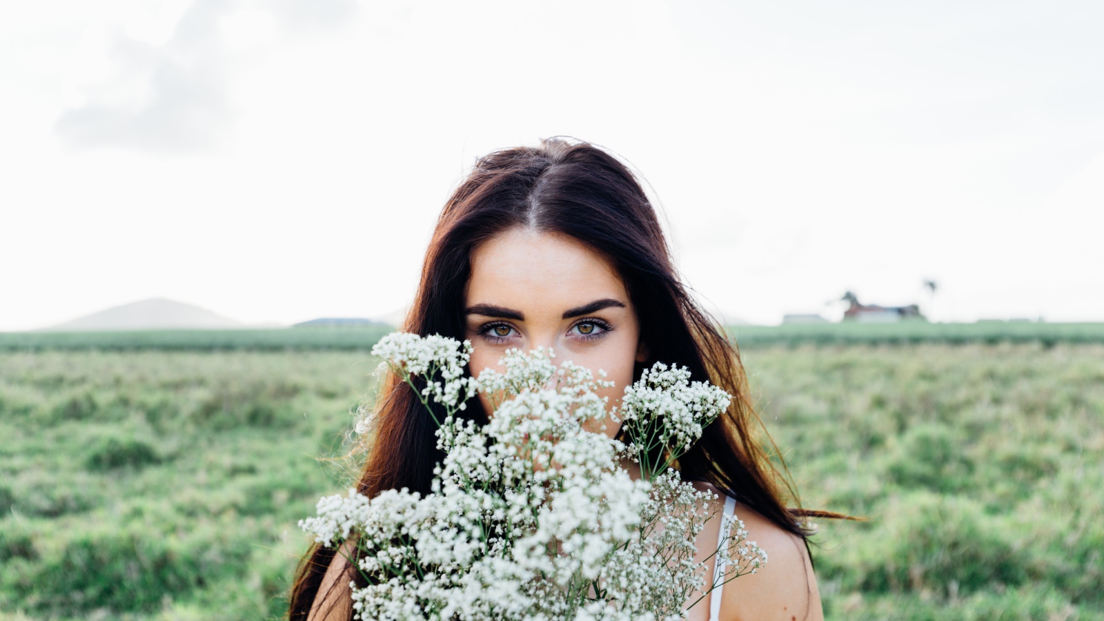 Красивая кареглазая девушка с букетом белых полевых цветов 