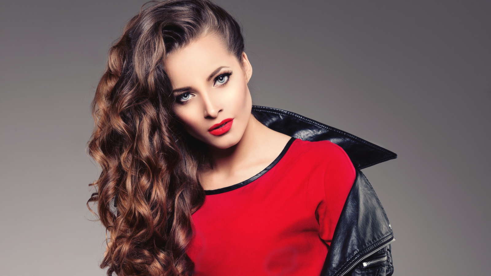 Красивая девушка в черной кожаной куртке и красном свитере